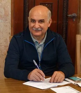 Rudolf sitting in a desk signing a document