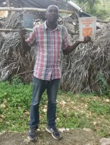 Haiti man standing holding books on each hand