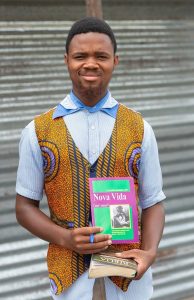 Mozambique young man standing holding biblical material